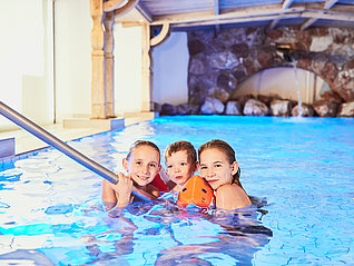 Drei Kinder bei Treppe des Indoorpools